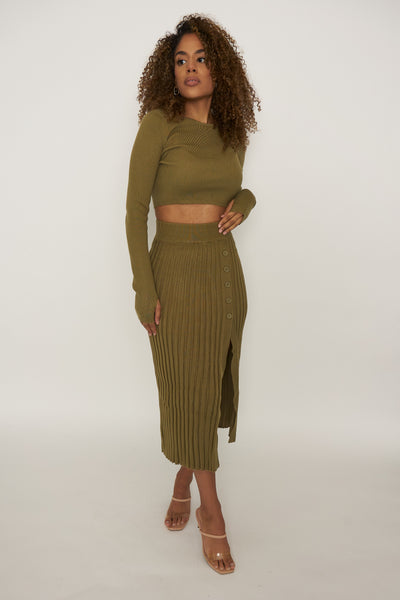 Show Me Leg is an olive green sultry pleated, mid-thigh slit sweater skirt paired with a long sleeve crop top. The crop top has a thumb hole feature that allows for easy layering and provides a sleek look. The skirt has a natural hourglass shape that helps accentuate your hips, slims your waist creating the hourglass effect when put on.
