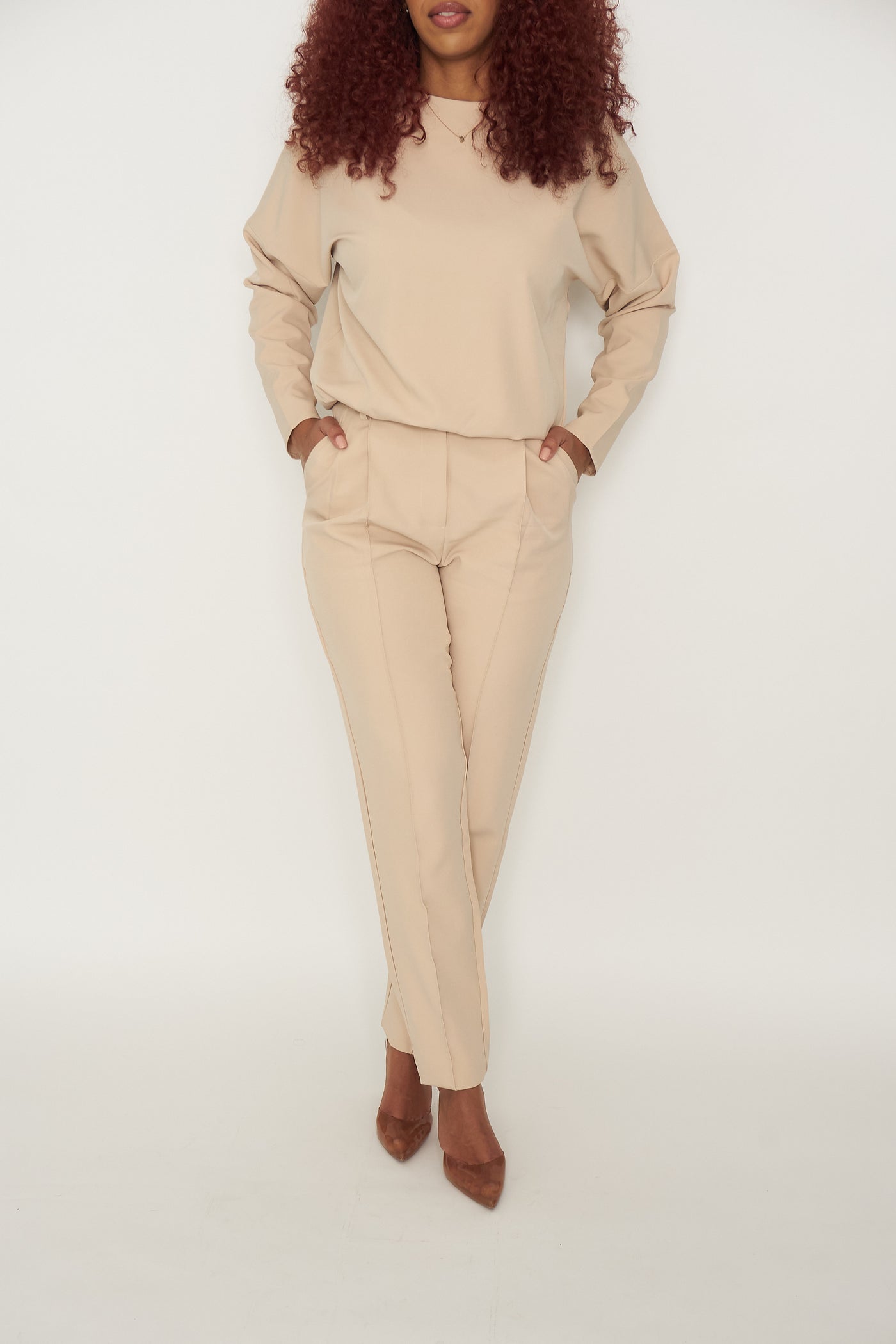 The Classy Girl Set is beige and comes with a long sleeve top that has a waistband bottom to always give the “tucked-in'' look without needing to tuck in the top. The bottoms come with zipper and button front with belt loops,